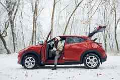 车森林美丽的年轻的女人在户外红色的汽车冬天时间
