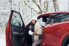 车森林美丽的年轻的女人在户外红色的汽车冬天时间