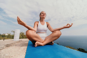 女人海普拉提运动快乐中年女人实践普拉提海滩海促进健康的生活方式户外健身冥想