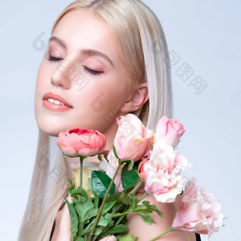 特写镜头年轻的风度翩翩的女人完美的化妆持有花