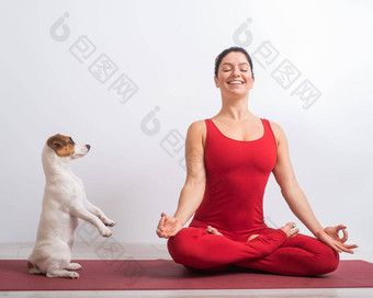 高加索人女人红色的连身裤坐在莲花位置狗瑜伽宠物