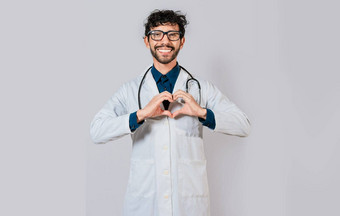 年轻的医生使心形状孤立的英俊的医生使心手势手快乐医生指出手指