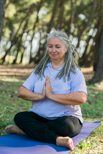 肖像成熟的女人灰色头发长发绺运动装放松冥想感觉Zen健身席公共公园在户外健康的活跃的生活方式高级上了年纪的人