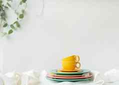 空黄色的杯明亮彩色的盘子白色表格覆盖亚麻桌布花能墙背景准备服务