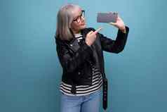 中间年龄业务现代夫人灰色的头发演示了智能手机模型明亮的背景