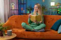 年轻的女人放松有趣的书把页面微笑享受文学采取休息沙发