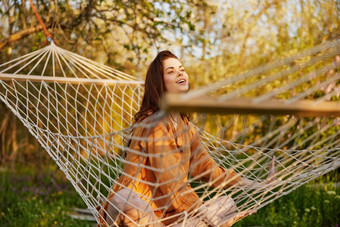 快乐的女人坐着网吊床自然放松享受射线设置太阳<strong>温暖</strong>的夏天一天水平<strong>照片</strong>主题户外娱乐