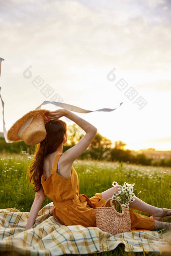 女人橙色衣服坐在洋甘菊场格子持有稻草他手享受日落