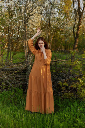 优雅的复杂的女人提出了站柳条栅栏别墅长橙色衣服