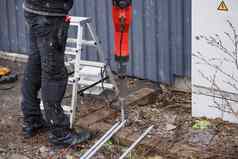 工人安装地面杆地面建筑工人工作衣服驱动器地球棒地面手提钻防止短电路
