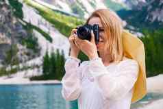 微笑金发女郎头发女摄影师专业相机采取照片湖