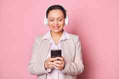 特写镜头美丽的女人智能手机滚动播放列表享受听音乐耳机孤立的粉红色的