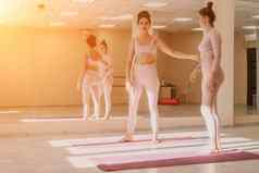 中间岁的运动女人健身教练粉红色的运动服装伸展运动普拉提瑜伽席工作室镜子女健身瑜伽健康的生活方式和谐