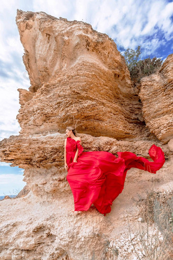 女人红色的丝绸衣服站海洋山背景衣服摇摆微风