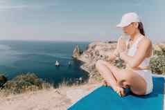 健身女人海户外锻炼瑜伽席辊公园海洋海滩女健身普拉提瑜伽例程概念健康的生活方式快乐适合女人锻炼橡胶乐队公园