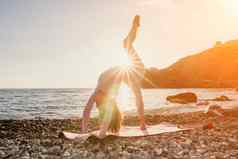 女人海瑜伽快乐女人黑色的头发普拉提环瑜伽席海卵石海滩女健身瑜伽概念健康的生活方式和谐冥想