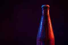玻璃啤酒瓶蓝红色光黑色的背景复制空间