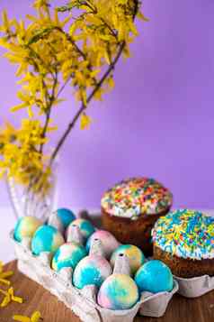 复活节蛋糕紫色的背景黄色的春天花复活节彩色的鸡蛋复活节食物最小的概念