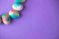 复活节作文色彩斑斓的鸡蛋购物车木兔子春天花紫色的背景复活节框架鸡蛋画紫色的颜色复制空间