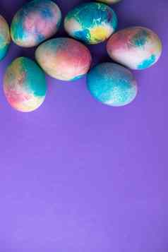 复活节作文色彩斑斓的鸡蛋购物车木兔子春天花紫色的背景复活节框架鸡蛋画紫色的颜色复制空间