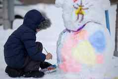 男孩油漆雪人冬天一天