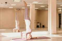 年轻的运动女人健身教练粉红色的运动服装伸展运动普拉提瑜伽席工作室镜子女健身瑜伽例程概念健康的生活方式和谐