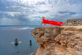 女人红色的丝绸衣服站海洋山背景衣服摇摆微风