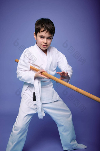 十几岁的男孩白色和服打架木剑合气道培训紫色的背景健康的生活方式武术艺术概念