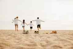 回来视图家庭父母孩子们享受有趣的持有手运行海滩