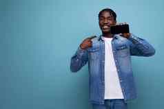 时尚的非洲男人。非洲式发型卷发展示智能手机模型蓝色的背景复制空间