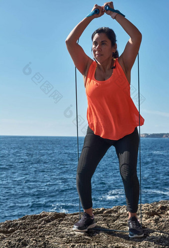 拉丁女人中年穿运动服装培训物理练习板材仰卧<strong>起坐</strong>攀岩者的一步燃烧卡路里保持适合在户外海穿耳机聪明的看