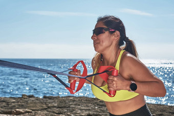 拉丁女人中年穿运动服装培训物理练习板材仰卧起坐攀岩者的一步燃烧卡路里保持适合在户外海穿耳机聪明的看
