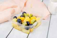水果沙拉菠萝芒果猕猴桃蓝莓塑料容器木背景