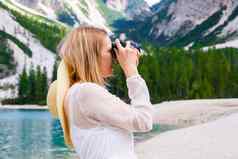 年轻的女人摄影师持有相机采取照片阿尔卑斯山脉
