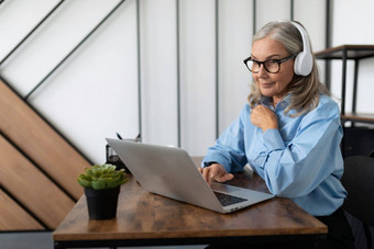 成熟的成人女人经济学家灰色的头发衬衫持有会议在线互联网耳机