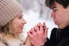 年轻的夫妇走冬天森林的家伙变暖女孩的手