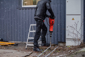 工人安装地面杆地面建筑工人工作衣服驱动器地球棒地面手提钻防止短电路