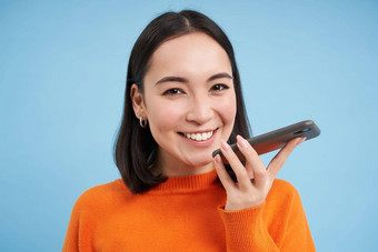 肖像亚洲女人记录的声音消息会谈扬声器持有移动电话口说话翻译演讲应用程序蓝色的背景