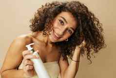 女人适用于奶油乳香卷曲的头发概念保护护理沙龙产品健康的微笑牙齿米色背景