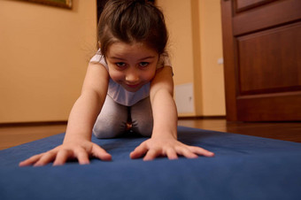 特写镜头前面拍摄可爱的孩子女孩伸展运动身体孩子<strong>构成</strong>锻炼瑜伽席在室内