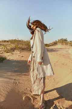 时髦穿着女人站摆姿势沙漠多风的天气