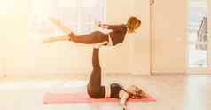 中间岁的女人黑色的头发健身教练紧身裤上衣伸展运动普拉提瑜伽席镜子女健身瑜伽例程概念健康的生活方式