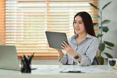微笑千禧女人阅读电子邮件检查每天例程数字平板电脑坐着现代首页办公室