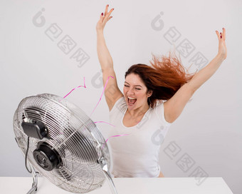 快乐的高加索人女人享受风吹电风扇白色背景