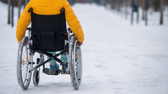高加索人女人残疾的人游乐设施椅子公园冬天回来视图女孩走轮椅