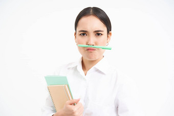 有趣的朝鲜文女人笔记本电脑持有笔嘴唇鼻子使脸站白色工作室背景