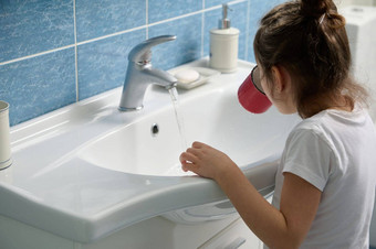 后视图可爱的孩子女孩冲洗口刷牙牙齿站白色陶瓷水槽首页浴室