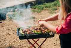 烧烤烧烤鸡肉西红柿绿色胡椒自然森林野营公园海背景女人烹饪在户外