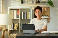 年轻的亚洲男人。学生看网络研讨会研究在线类移动PC数字平板电脑在线学习概念