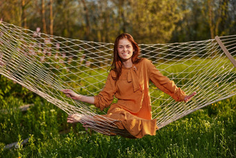 水平<strong>照片</strong>美丽的红发女人说谎吊床享受休息长橙色衣服<strong>温暖</strong>的夏天一天微笑幸福的相机